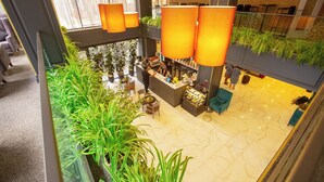 A hotel lobby with a central bar area, seating, and a large indoor plant arrangement. - Premium Park Hotel (Baku)