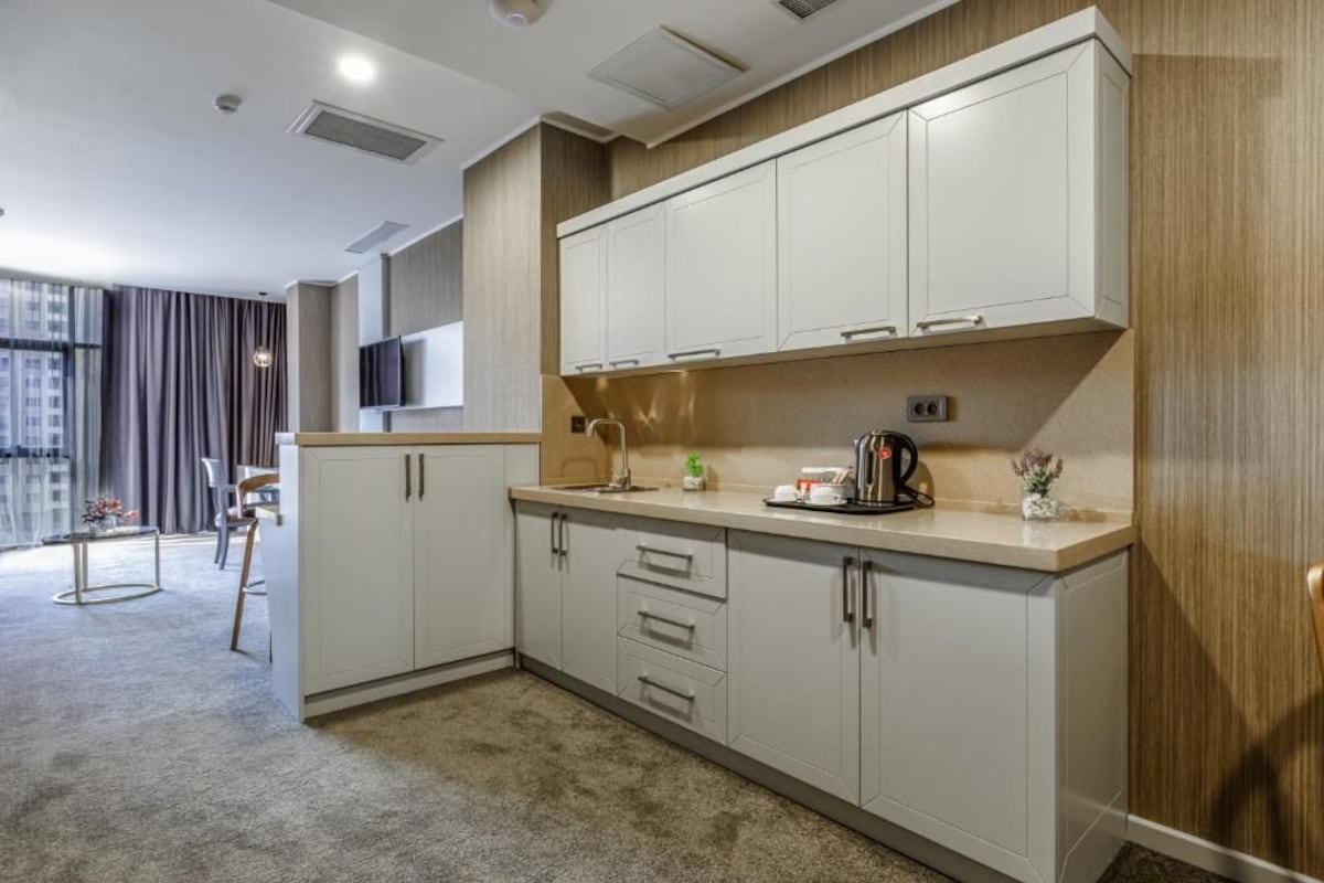Una cocina moderna con armarios blancos, una encimera y una cafetera.