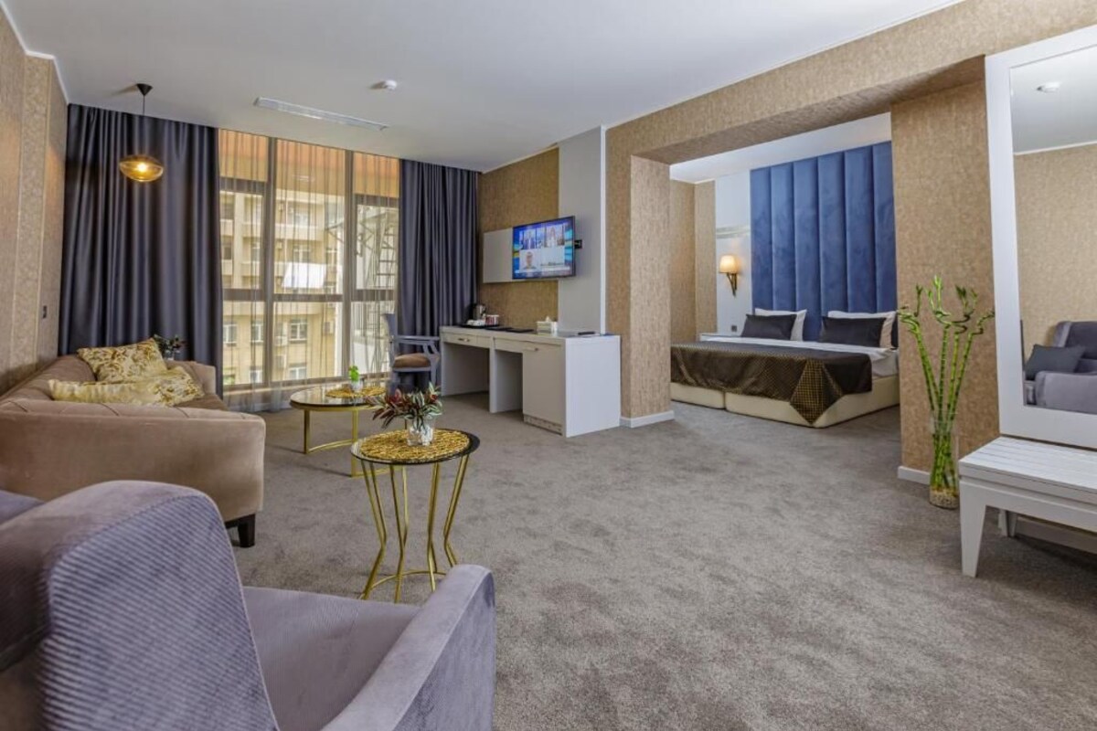 A hotel room with a sofa, a desk, a bed, and a TV.