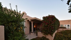 Uma casa moderna com varanda coberta, um jardim bem cuidado e um céu limpo.