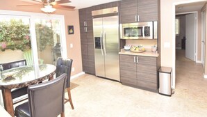 Uma cozinha moderna com geladeira, micro-ondas e uma área de refeições com cadeiras e mesa.