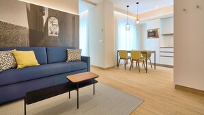 A modern living room with a sofa, a coffee table, and a dining area with chairs and a table. - Tándem Pópulo (Cádiz)