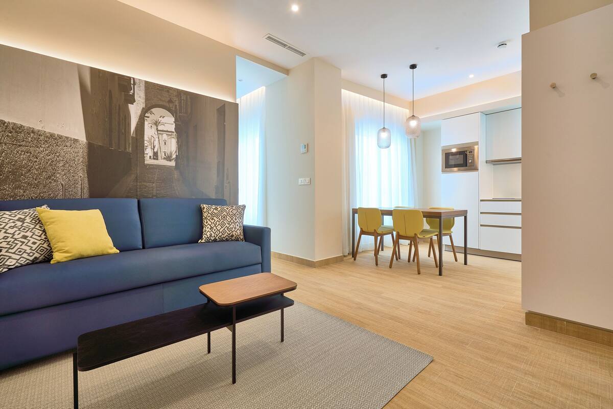 A modern living room with a sofa, a coffee table, and a dining area with chairs and a table.
