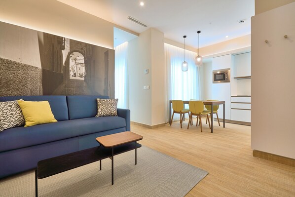 A modern living room with a sofa, a coffee table, and a dining area with chairs and a table. - Tándem Pópulo (Cádiz)