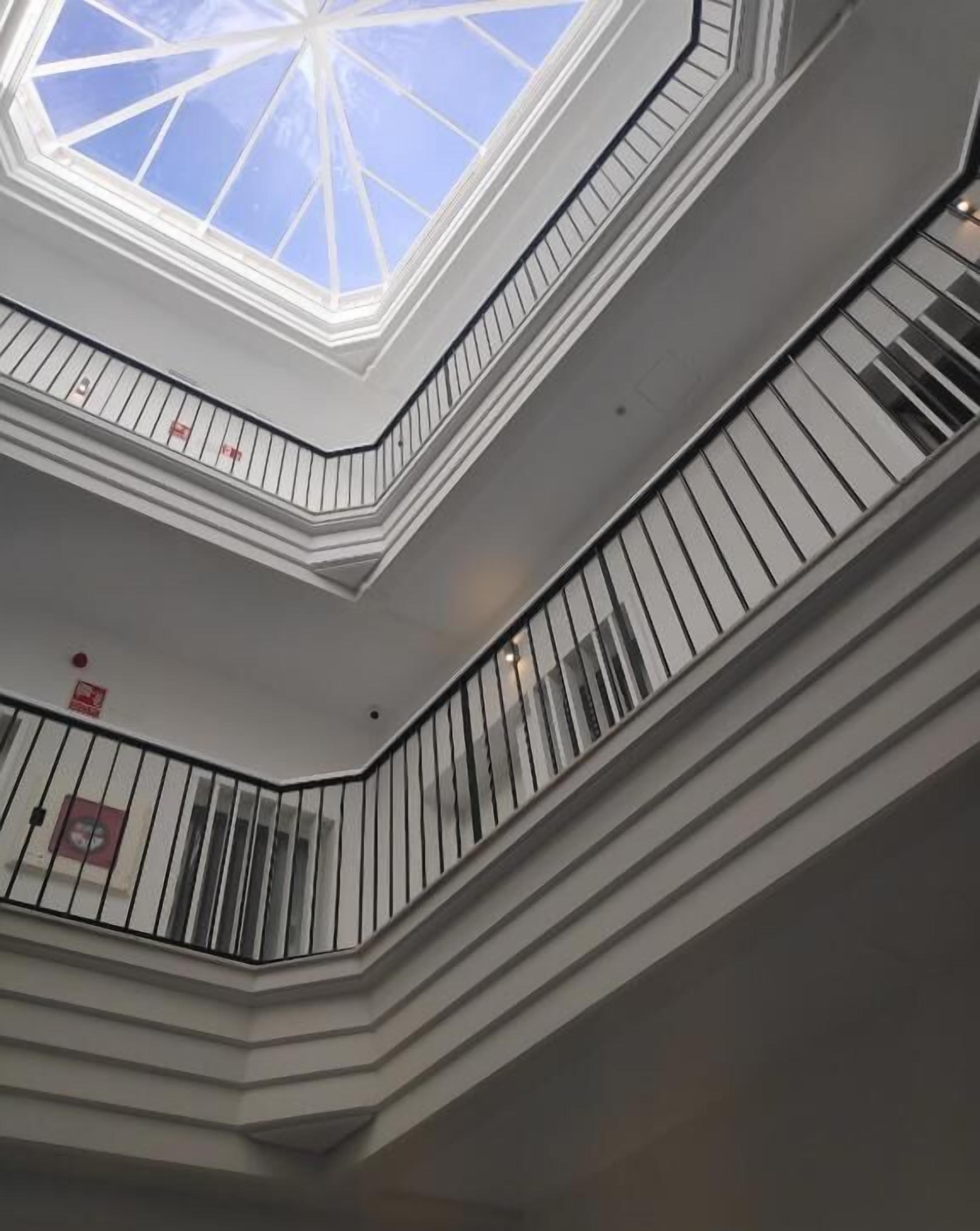 Een meerlaags interieur met dakraam, leuningen en een geometrisch plafondontwerp.