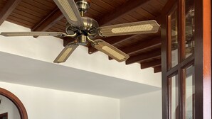 Un salon avec un canapé beige, une table basse en verre et un ventilateur de plafond.