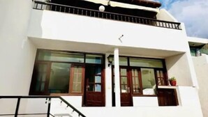 Une maison moderne à deux étages, dotée de grandes fenêtres, d’un balcon et d’un escalier menant à l’étage supérieur.
