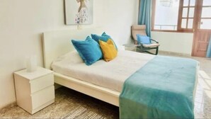 Une chambre à coucher avec un lit, une table de chevet, une chaise et une fenêtre avec des rideaux.