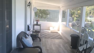 Relax on the covered porch with a view, featuring a comfortable seating area with wicker chairs and a small table.