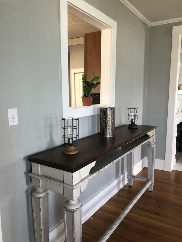 A hallway with a dark wooden console table, a mirror, and a potted plant.