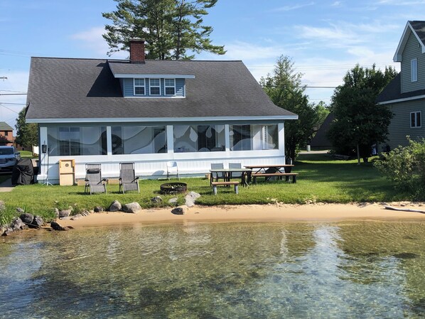 A house with a large porch, a dining area, and a small pond in front. - Torch Lake Oasis: Serene Views & Waterfront Bliss Await! (Rapid City)