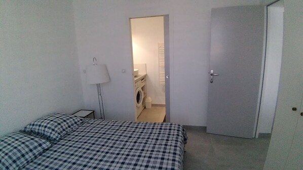 A bedroom with a bed, a bedside lamp, and a door leading to a bathroom.