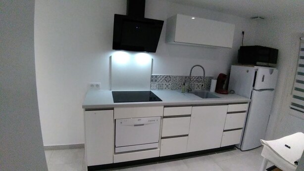 A compact kitchen with a built-in dishwasher, a microwave, and a sink. - New 2-room apartment in family home 100 m from beach and port (Capbreton)