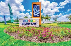 Schild für Storey Lake mit einem tropischen Wandgemälde, umgeben von bunten Blumen und Palmen.