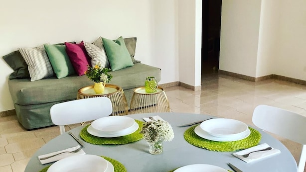 Un coin repas avec une table ronde dressée pour quatre personnes, entourée de chaises.