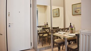 A dining area with a table set for four, chairs, a vase with flowers, and a painting on the wall. - A Skip Away from the Acropolis Museum (Athens)