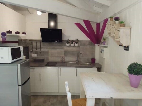 A compact kitchen with white cabinets, a microwave, a sink, and a flat-screen TV mounted above it. - Chalet in Gascony (Vergoignan)