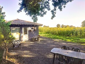 Una cabaña rústica con un patio de grava, una mesa y sillas.