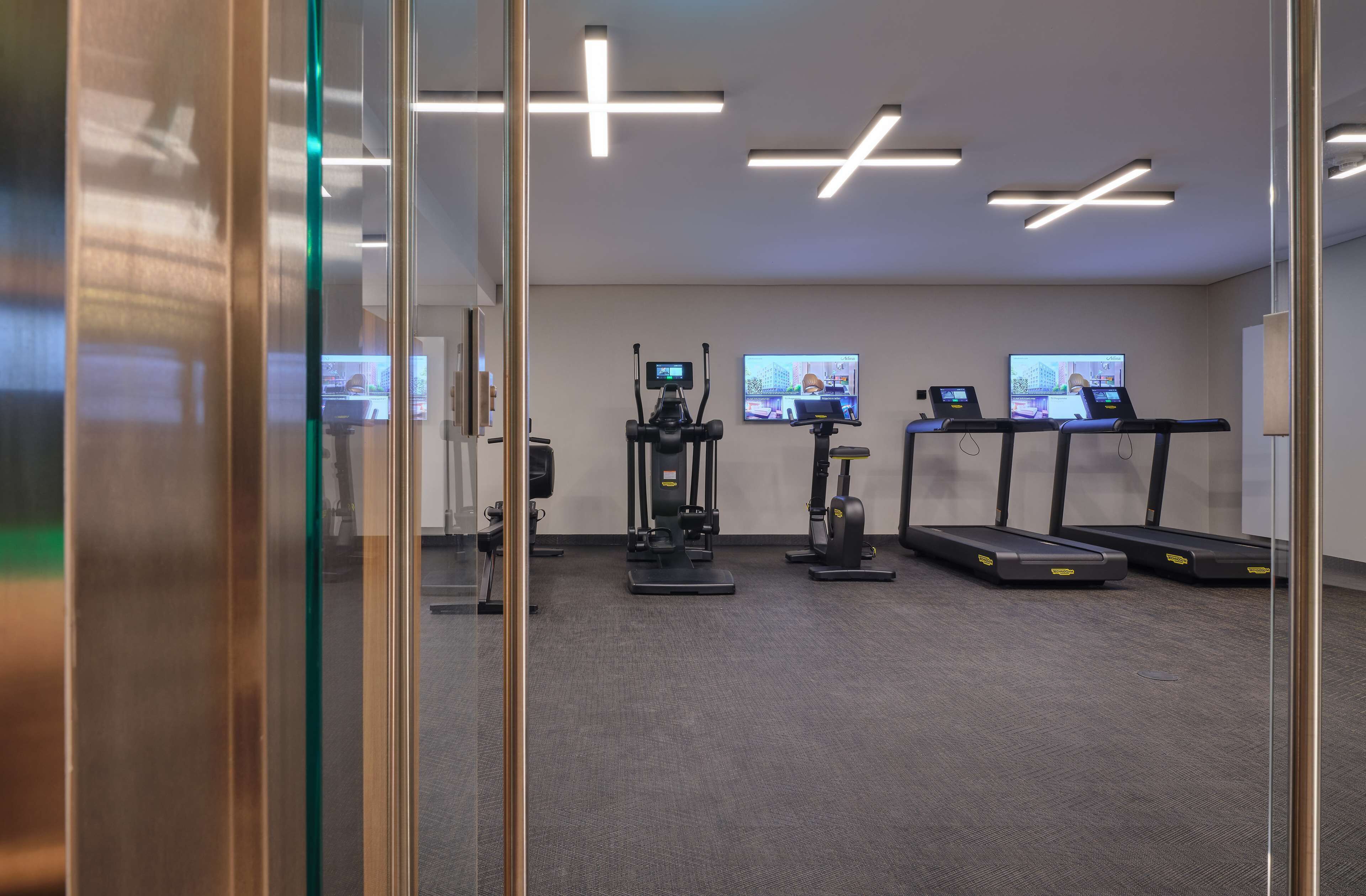 A modern gym with treadmills, a stationary bike, and a rowing machine.