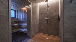 Moderni kylpyhuone, jossa on suihku, penkki ja sauna.
