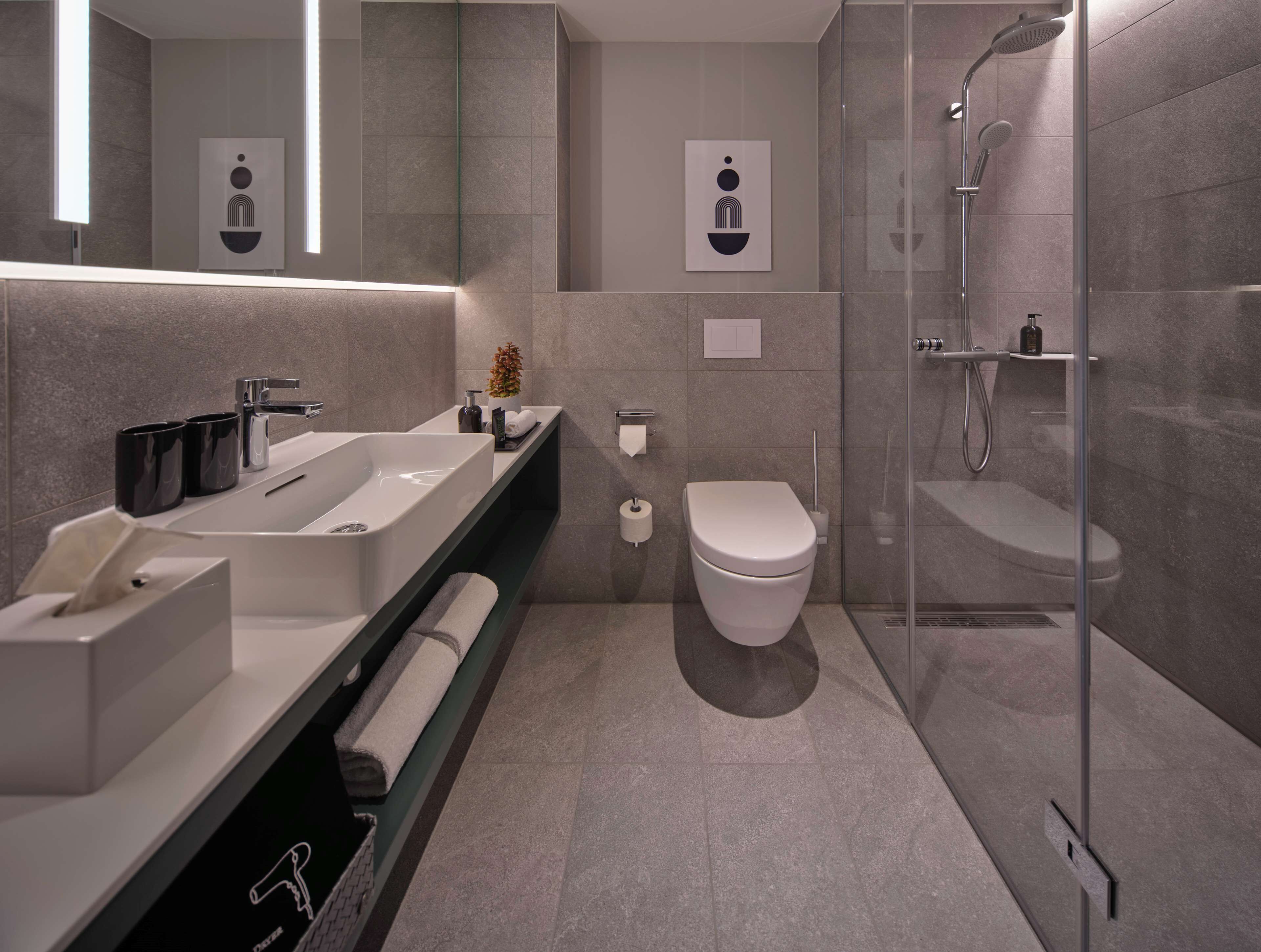 Un baño moderno con lavamanos grande, inodoro y ducha a ras de suelo.