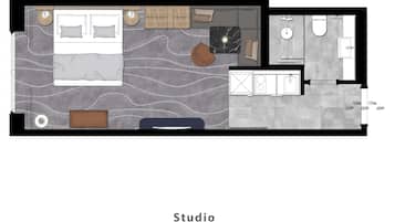 A studio apartment layout with a bed, seating area, kitchenette, and bathroom.