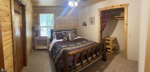 Een gezellige slaapkamer met een houten bed, een nachtkastje, een raam en een deur.