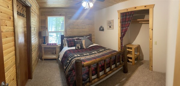 A cozy bedroom with a wooden bed, a nightstand, a window, and a door.