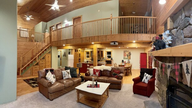 A spacious living area with a high ceiling, wooden staircase, and a cozy fireplace. -  COZY BEAR LODGE - BEAUTIFUL MOUNTAIN GET AWAY (Island Park)