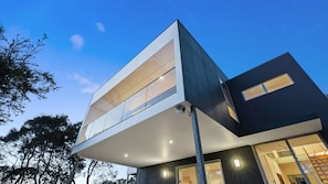 A modern multi-story building with a flat roof, large windows, and a balcony.