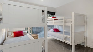 A room with bunk beds, a window, and a view of trees.