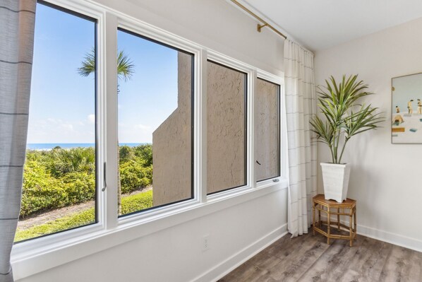 A room with large windows, a potted plant, and a framed artwork on the wall. - Luxury Oceanfront Villa in Windsong - Fully Updated and Close to Pool! (Amelia Island)