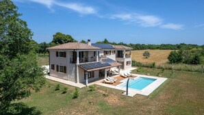 Une maison à deux étages avec une piscine, des panneaux solaires et un jardin.
