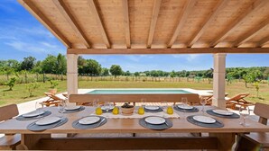 Un espace de restauration en plein air avec vue sur la piscine, doté de tables et de chaises en bois.