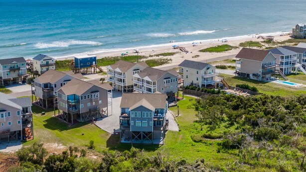 A coastal residential area with multiple two-story houses, some with balconies, near a beach with a clear view of the ocean. - Sunset Cove | Sound Views + Walk to the Beach! (North Topsail Beach)