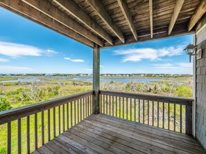 A wooden deck with a view of a marshy landscape and distant buildings. - Sunset Cove | Sound Views + Walk to the Beach! (North Topsail Beach)