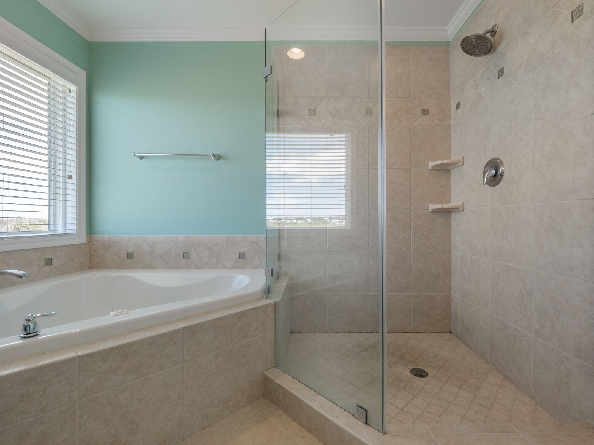 A modern bathroom with a glass-enclosed shower, a freestanding bathtub, and a window providing natural light.