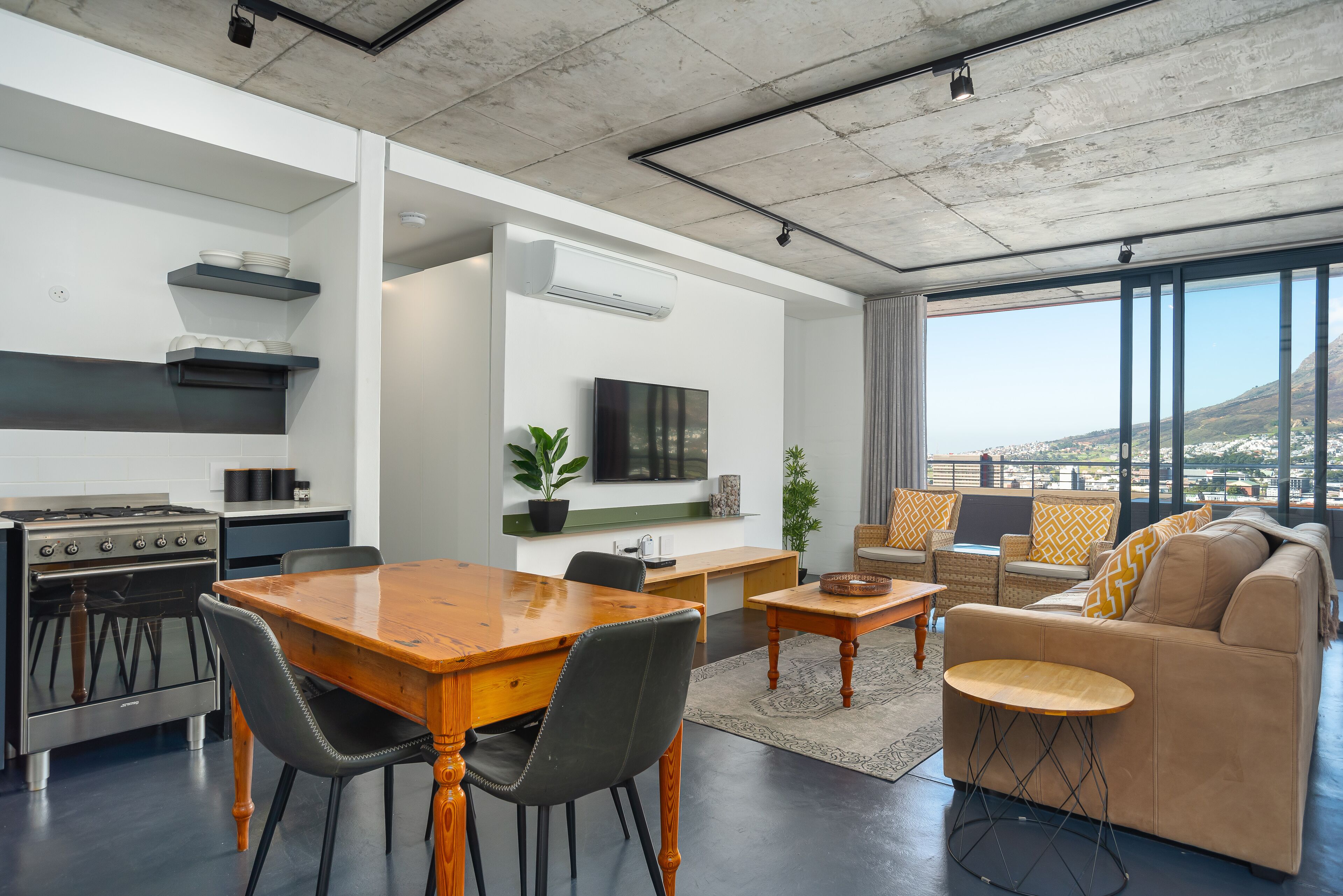A modern living space with a dining area, kitchen, and seating area with a view.