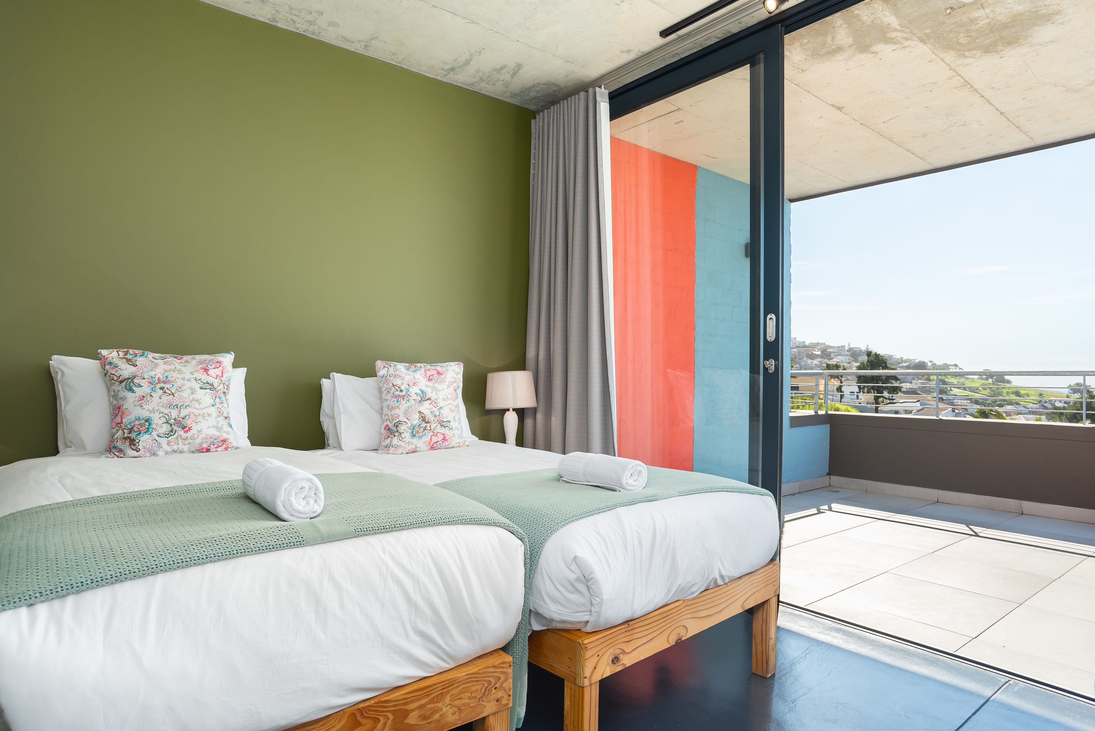 A hotel room with two beds, a balcony, and a view of the city.