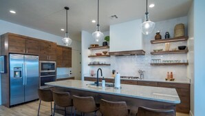 A modern kitchen with a central island, bar stools, stainless steel appliances, and wooden cabinetry. - Arcadia 53 | DOG FRIENDLY * PRIVATE Hot Tub * Arcade Games * Sleeps 21 (Santa Clara)