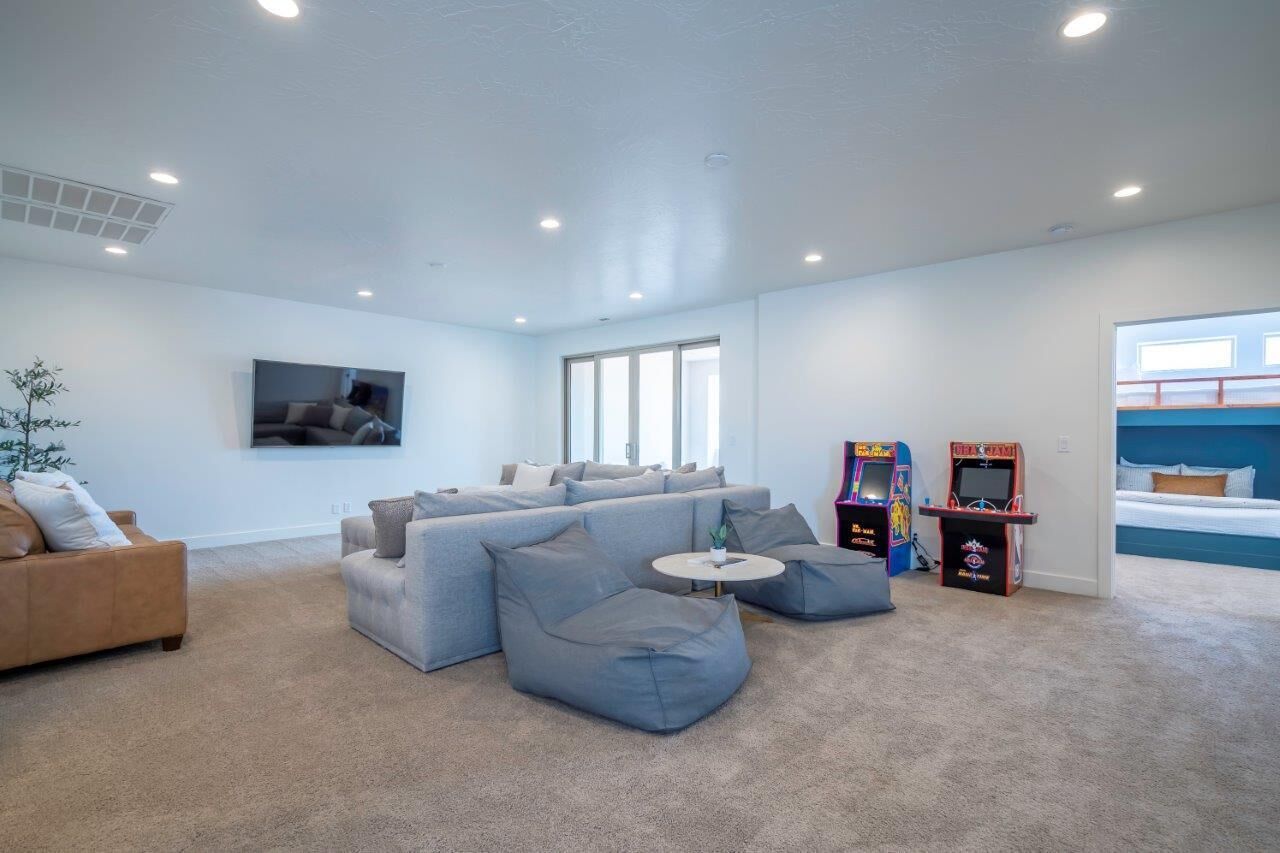 Un salon moderne avec un canapé d’angle, une petite table ronde et des jeux d’arcade.