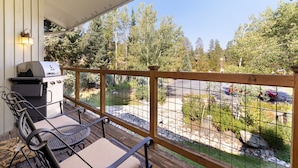 Un espacio de estar techado al aire libre con una parrilla y sillas, con vistas a un jardín y un estacionamiento.