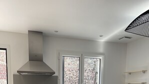 A modern kitchen with a gas stove, stainless steel sink, and a window with a view of a brick wall. - Louise's Cottage, downtown Saint Valery sur Somme (Saint-Valery-sur-Somme)