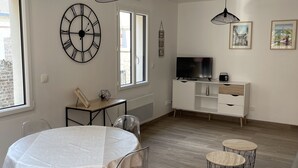 A modern living room with a dining table, chairs, a TV, and two pendant lights. - Louise's Cottage, downtown Saint Valery sur Somme (Saint-Valery-sur-Somme)