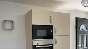 A compact kitchenette with a microwave, oven, and a small cabinet. - Louise's Cottage, downtown Saint Valery sur Somme (Saint-Valery-sur-Somme)