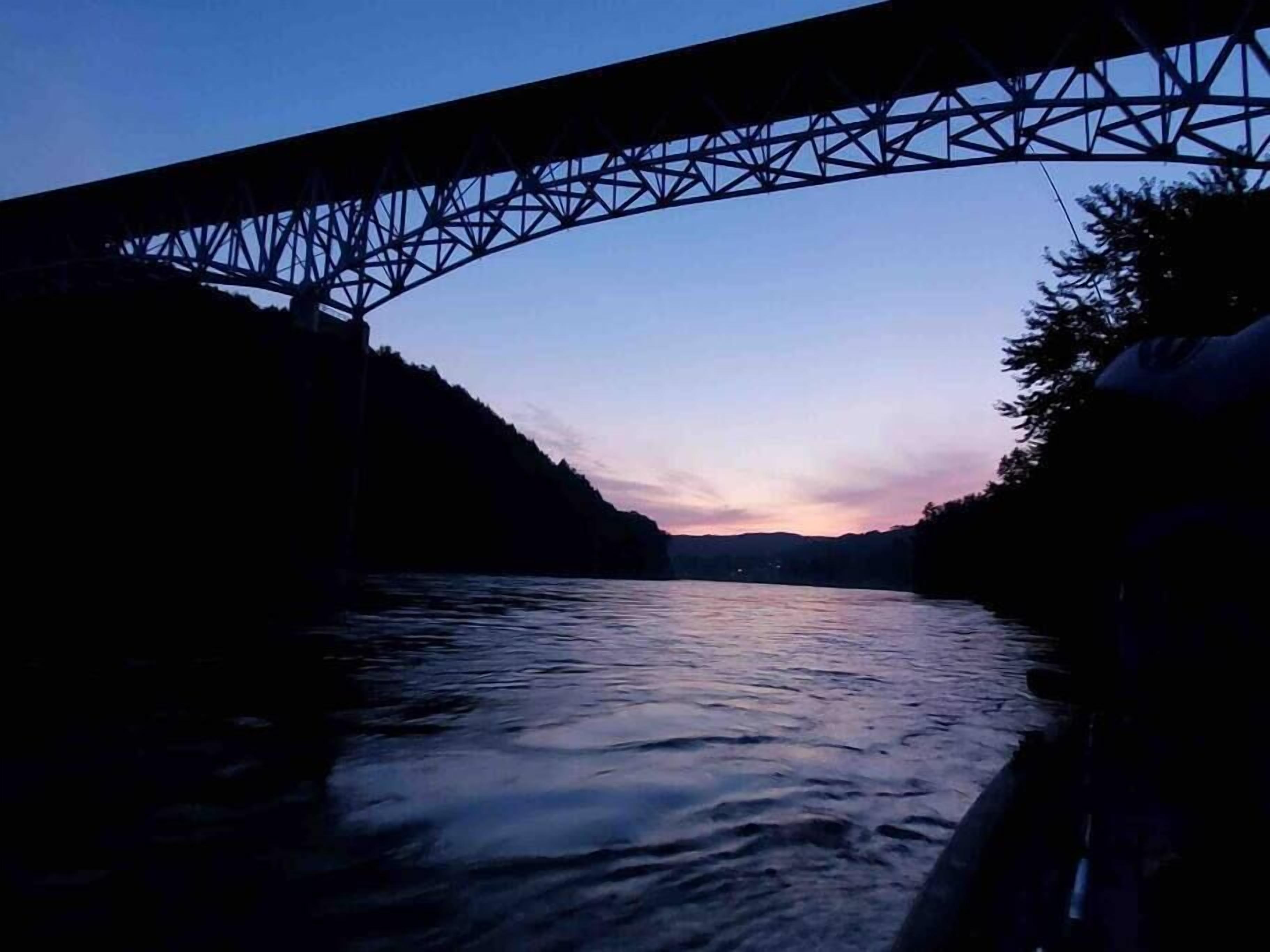 A bridge over a river at dusk with a clear sky.