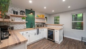 Une cuisine moderne avec des armoires blanches, un plan de travail en bois et un dosseret de carrelage vert.