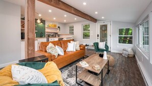 Un salon moderne avec un plafond en bois, un canapé en cuir, un fauteuil vert et une table basse.