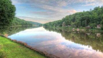 A calm river with a grassy bank and trees on both sides.