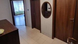 A hallway with a wooden door, a mirror, and a tiled floor. - Apartment Lozenets, Sofia, Bulgaria (Sofia)